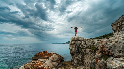 Woman with outstretched arms enjoying the wind and breathing fresh air on top of a rocky mountain...