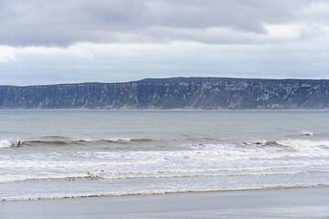 Seashore with waves, a cliff on the horizon