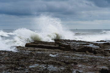 The wave crashes against rocky coastline