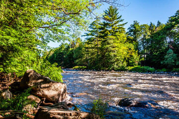 Rivière du Nord, just north of Montreal, roars over rocks, its banks adorned with stones and lush...