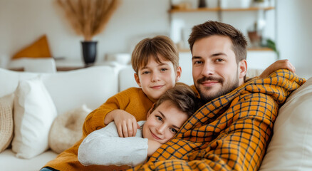 Obraz premium Man and two children wrapped in blanket on couch in living room.