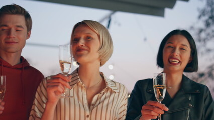 Emotional students clinking prosecco in sunset bar terrace closeup. People party