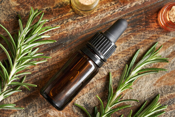 A bottle of aromatherapy essential oil with fresh rosemary plant on a table