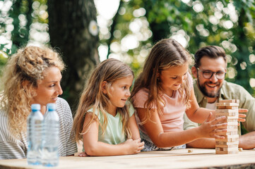 Girl is taking wooden block from wooden tower and playing jenga.