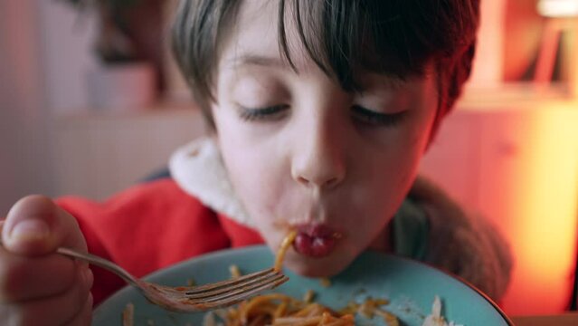 Small boy enjoying plate of pasta for supper, close-up face of 5 year old child eating spaghetti