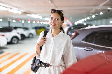 Young woman poses standing at underground parking