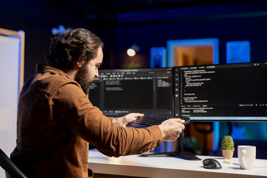 Angry man raging while doing software quality assurance, feeling mad after seeing errors in source code on computer screen. Frustrated developer ready to smash keyboard after finding coding issues