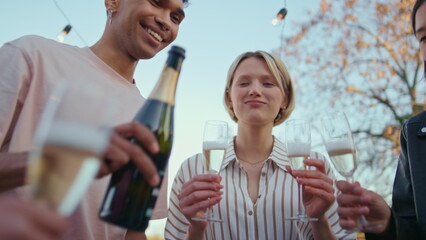 Diverse friends pouring drink glasses on birthday celebration in park closeup
