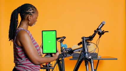 Woman holds green screen tablet, using it to advertise bike repair shop, empty placeholder for...