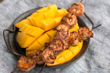 sliced mango and fried shrimp on skewers. Outdoor recreation, serving dishes