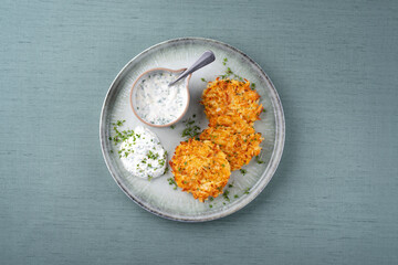 Traditional parsnip potato pancakes with chives and quark dip served as a top view on a Nordic...