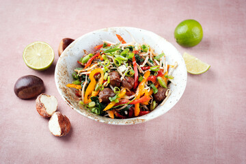 Traditional Asian wok spinach with chestnuts, pepper strips and soy sprouts served as a close-up in...