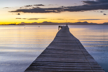 Wooden jetty at sunrise in the bay at Port d'Alcudia in Mallorca
