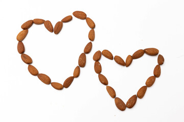 Two heart shapes made of whole almonds isolated on a white background