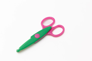 Bright pink and green scissors isolated on a white backdrop