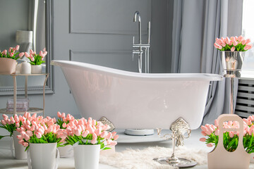 A bathroom with a large white bathtub and a few pink flowers