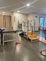 A well-equipped physical therapy room with various rehabilitation equipment, including parallel...