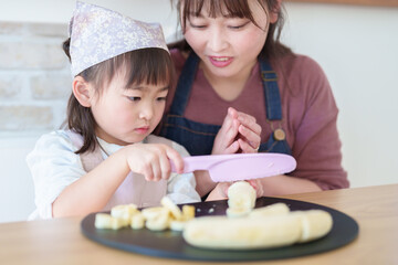 Obraz na płótnie Canvas お母さんと一緒に料理を手伝う女の子