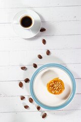 Delicious cream and pine nuts tartlet with chocolate flakes and a cup of coffee.