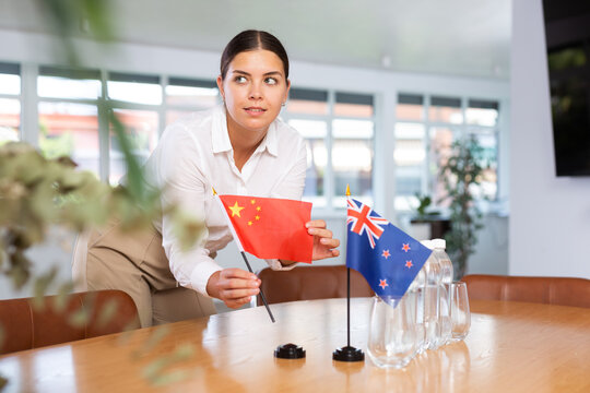 Preparing for business negotiations - woman sets small flags of countries of China and Australia on the table