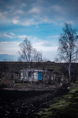 Old abounded houses in the old village . Spring mystery countryside . House in forest , blue clouds . Sunset over the hose . Damaged houses 