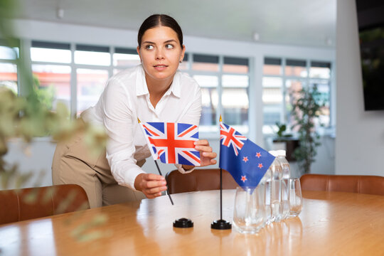Preparing for business presentation - secretary places flags of Great Britain and Australia on the negotiating table