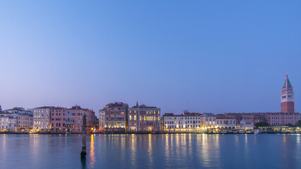 Panoramic view from Canal Grande at Campanile and facades of typical buildings during blue hour,...