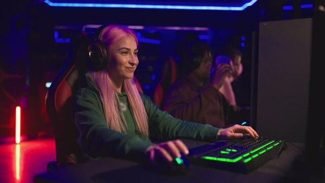 Cybersport woman gamer with pink hair playing a video game with her team