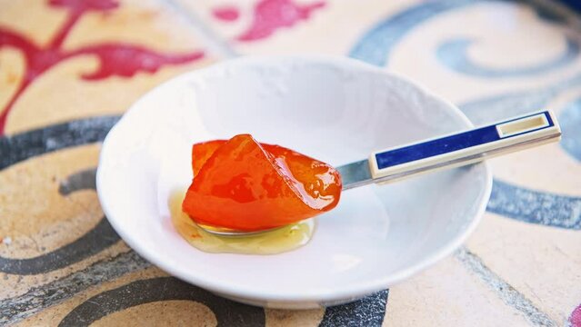 Spoon sweet Greek dessert with sugar syrup, bitter orange preserve on white plate with spoon from Ikaria island, Greece longevity blue zone