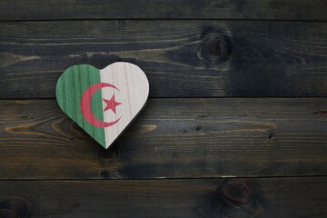 wooden heart with national flag of algeria on the wooden background.