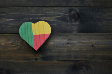 wooden heart with national flag of benin on the wooden background.