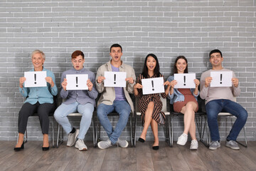 Applicants holding paper sheets with exclamation marks near grey brick wall