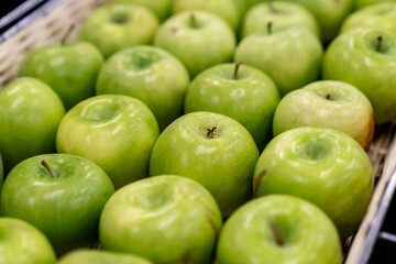 Boxes of juicy group green apples in the supermarket. sold in market, supermarket. a pile of fresh green apples neatly arranged in a fruit shop, fruits background concept
