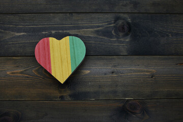 wooden heart with national flag of guinea on the wooden background.