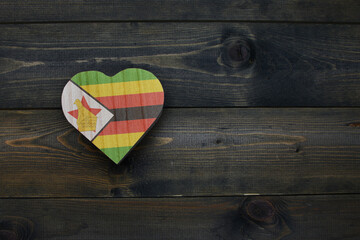 wooden heart with national flag of zimbabwe on the wooden background.
