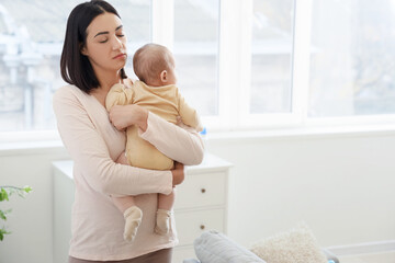 Tired young woman with her baby suffering from postnatal depression at home