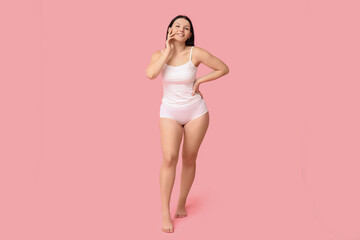 Fototapeta na wymiar Body positive woman in underwear smiling on pink background