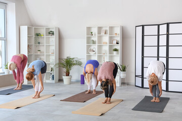 Group of sporty mature women doing yoga in gym