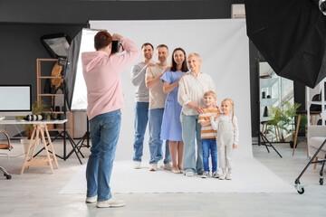 Male photographer taking picture of big family in studio - 776556481