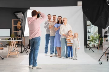 Tuinposter Male photographer taking picture of big family in studio © Pixel-Shot