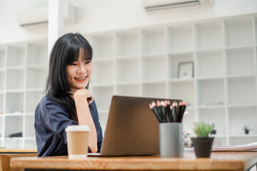 Cheerful businesswoman with braces smiling while working on her laptop in a bright, contemporary office space.