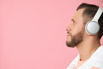 Young man in modern headphones on pink background
