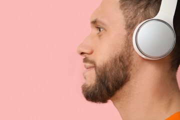 Young man in modern headphones on pink background, closeup