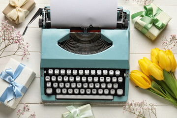 Composition with vintage typewriter, gift boxes and tulips for Women's Day on white wooden table