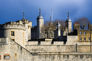 External view of walls and towers of Tower of London under dark sky