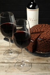 Delicious chocolate truffle cake and red wine on wooden table
