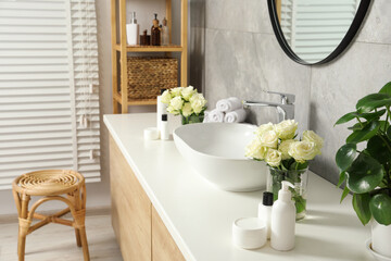 Beautiful roses and bath accessories near sink in bathroom