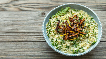 Lemon risotto with arugula and fried shiitake mushrooms. Rustic wooden table. Copy space. 