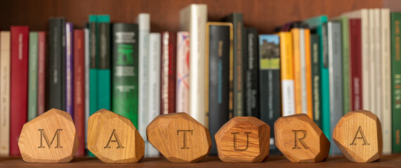 Matura text (polish word for end of school exam) written on irregular wooden blocks. Shelf with...