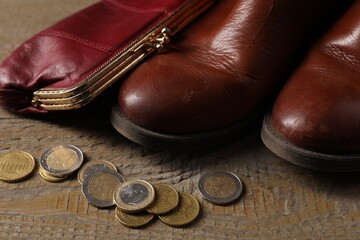 Poverty. Old boots, wallet and coins on wooden table, closeup